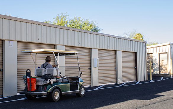 A Family Storage Resident driving past 10 by 10 storage units in a Golf Cart.